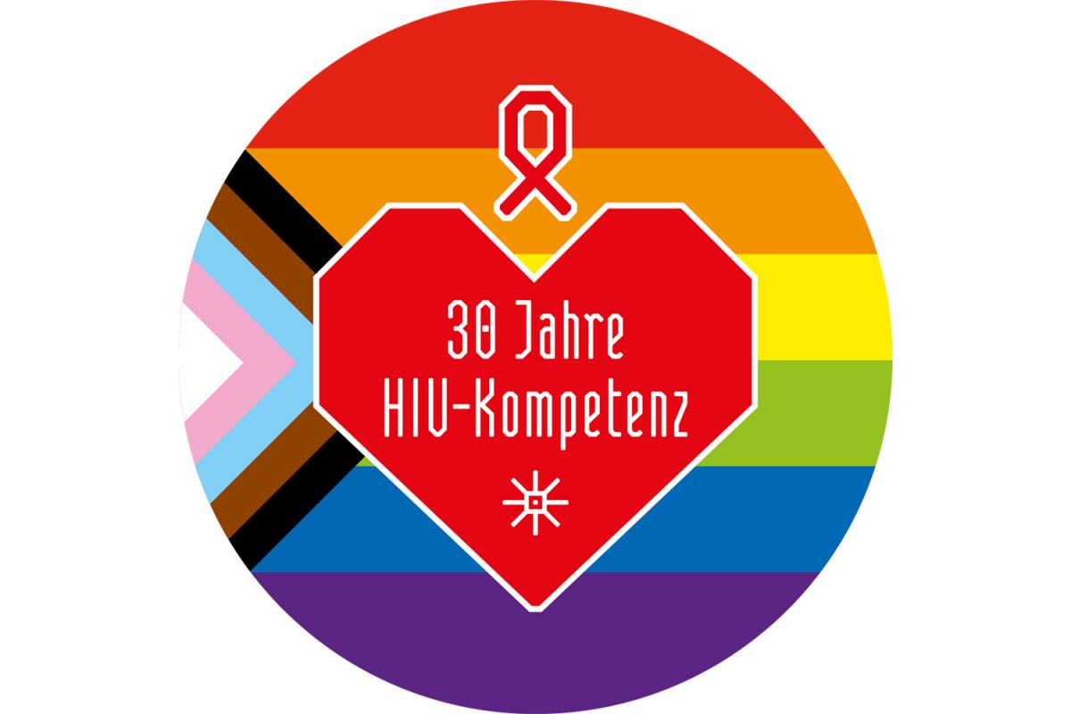 Rundes Logo mit progressiver Regenbogenflagge und rotem Herz in der Mitte. Darin steht