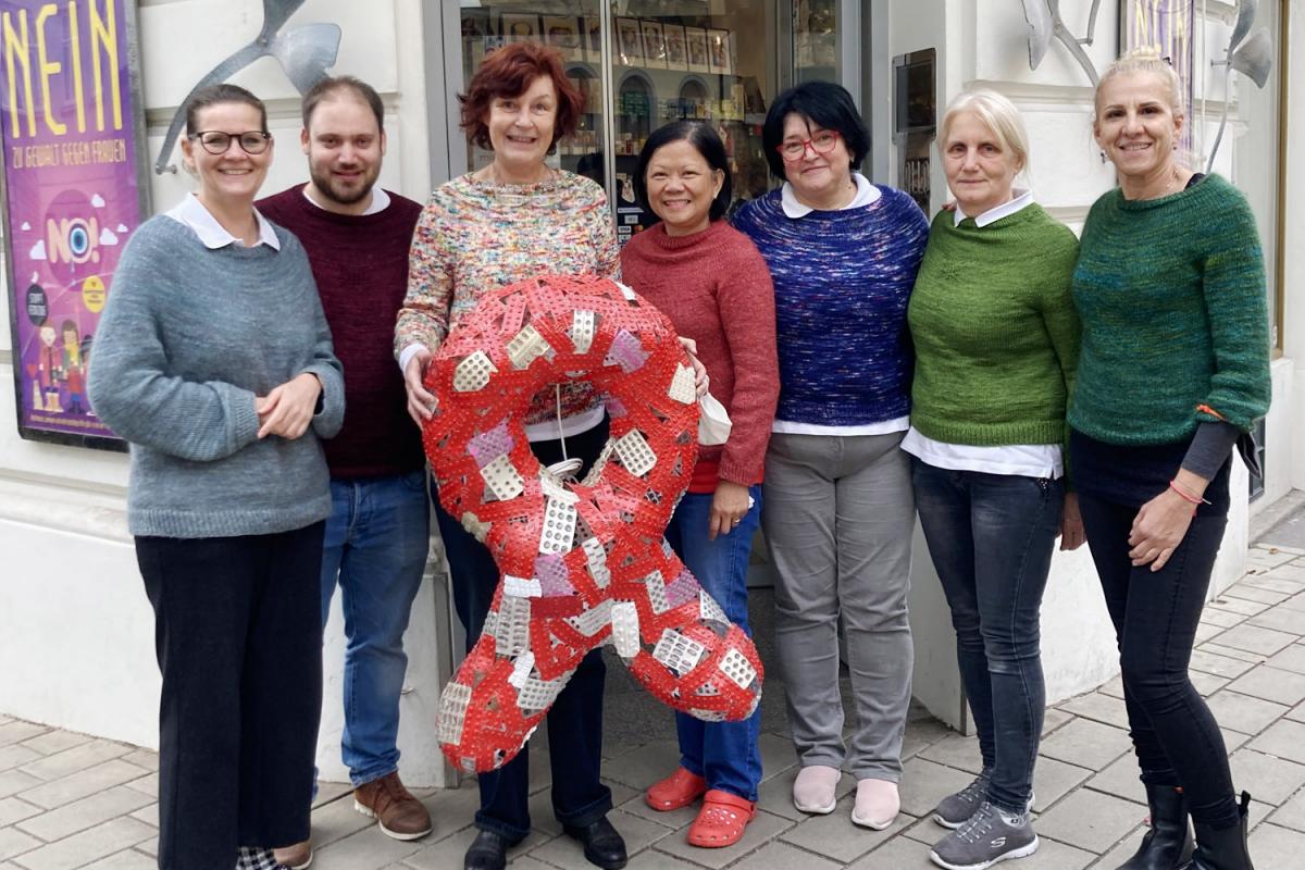 Team der Marien Apotheke mit Mag. pharm. Karin Simonitsch, das einen großen Red Ribbon aus leeren Medikamentenblistern hält