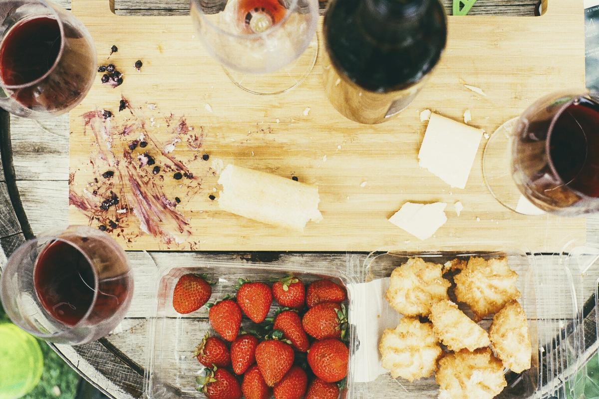 Tisch von oben betrachtet mit Rotweingläsern, Keksen, Käse und Erdbeeren