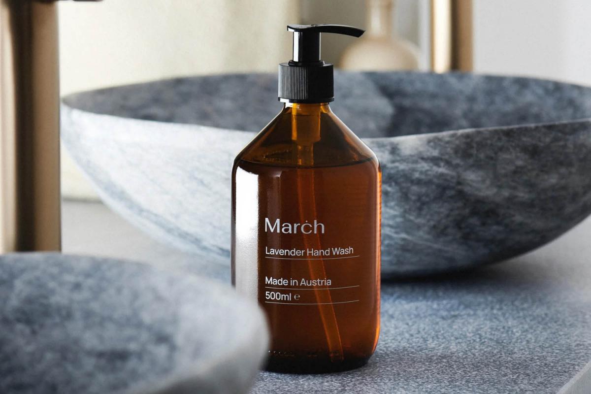 March Care Lavendel-Flüssigseife in dunkelbrauner Glasflasche vor Marmor-Waschbecken